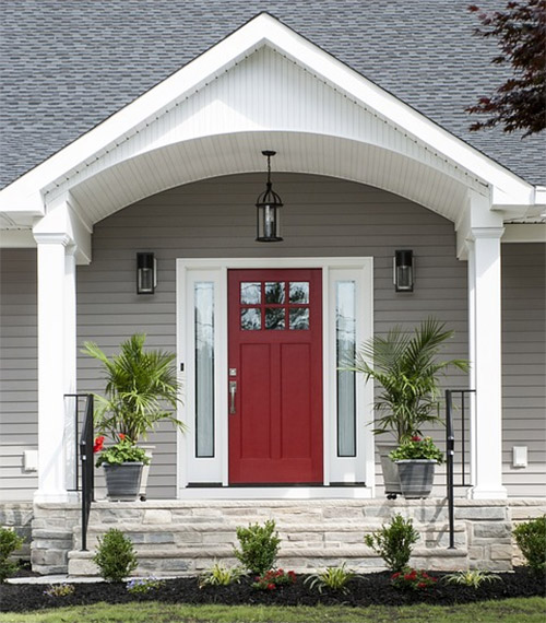 An entryway for a home, the trim is white, the siding is tan/light tan, and the front door is red.