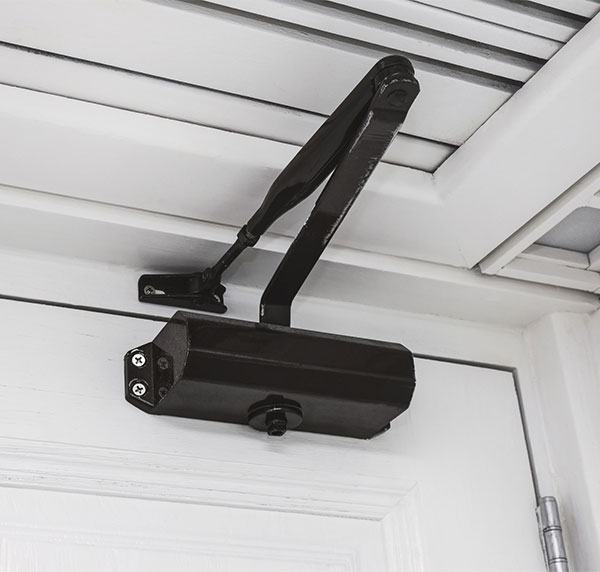 A black door closer installed on a white door and door frame.